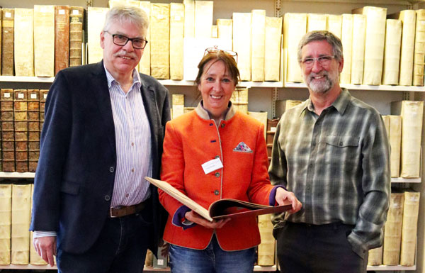 Späte Rückkehr: Dr. Hans Jacobs, Angela Buske (stellvertretende Bibliotheksleitung) und Breck Bartholomew mit dem verschollenen Bibliotheksband. Foto: HL
