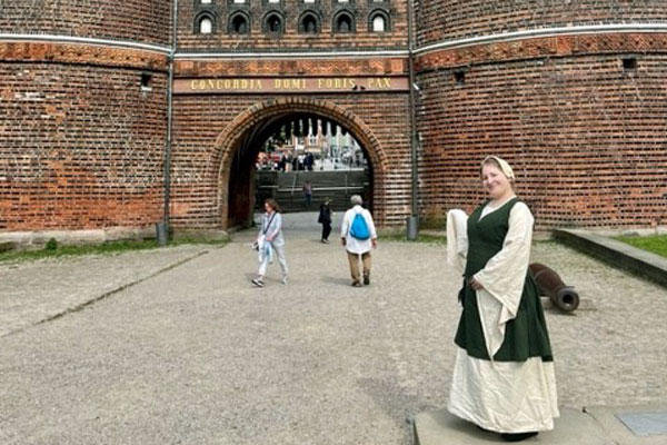 Carolin Täubert kostümiert als „Kaufmannsfrau Broling“, vor dem Holstentor. Die öffentlichen Führungen finden ohne Kostümierung statt. Foto: Lübecker Museen 