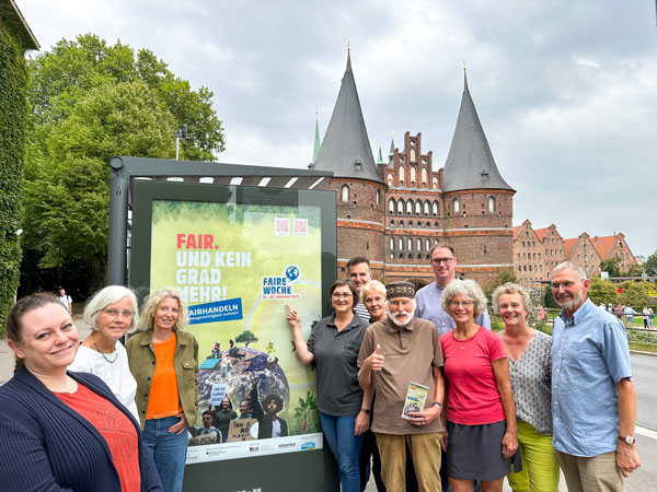 Mitglieder der Steuerungsgruppe Fairtrade Stadt Lübeck und Bürgermeister Jan Lindenau vor einem der Plakate am Holstentor. Fotos: Fairtrade Stadt Lübeck
