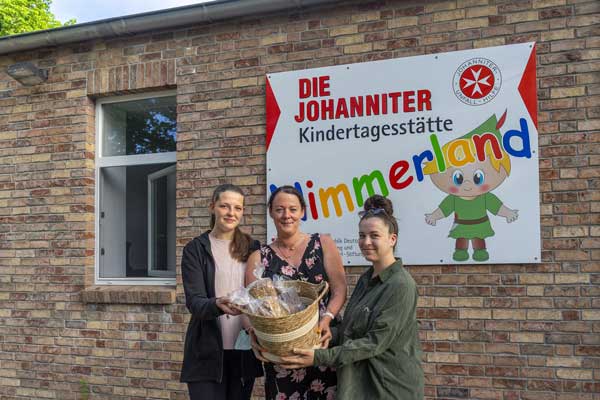 Nele Baer, Jessica Bahr und Justine Schürer aus der Kita Nimmerland freuen sich über die erste Lieferung des Bio-Brotes. Foto:  Johanniter-Unfall-Hilfe e.V.