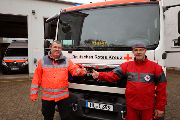 Olaf Schmidt, Katastrophenschutzbeauftragter des DRK Lübeck, mit Helfer Hendrik Leptien weisen auf den Warntag am Donnerstag hin. Foto: DRK