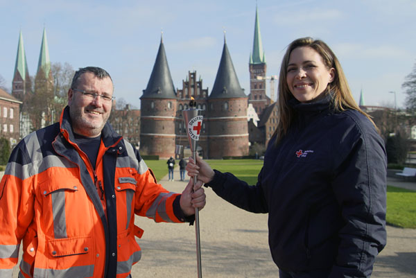 Ariane Schöneborn vom DRK Lübeck nahm die Fackel am Holstentor von Olaf Schmidt vom DRK-Rettungsdienst entgegen. Foto: VG