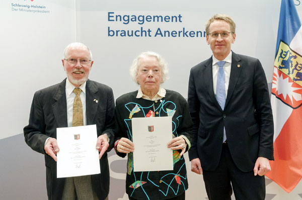 Ministerpräsident Daniel Günther (rechts) überreichte Karin und Dieter Weber die Ehrennadel des Landes. Foto: Frank Peter