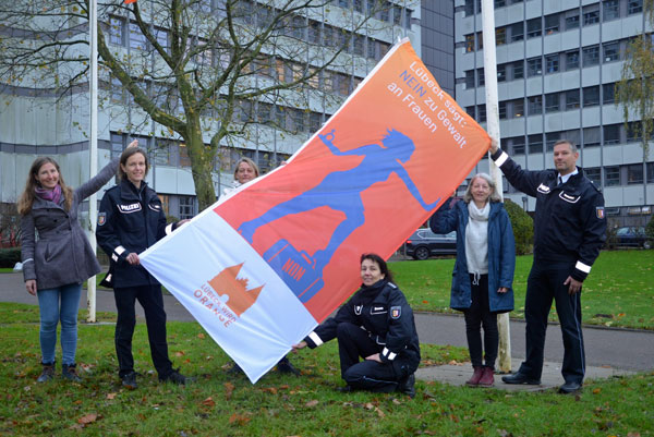 Mitarbeiterinnen und Mitarbeiter der Polizeidirektion Lübeck hissen die Flagge zum Orange-Day. Foto: Polizeidirektion Lübeck