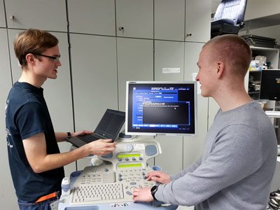 Jan Wichelmann und Luca Wilke vom Institut für IT-Sicherheit untersuchen ein Ultraschallgerät. Foto: Uni Lübeck